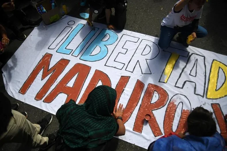 Personas afines a Maduro y una pancarta durante una marcha por su liberaci&oacute;n. (Xinhua/Marcos Salgado)